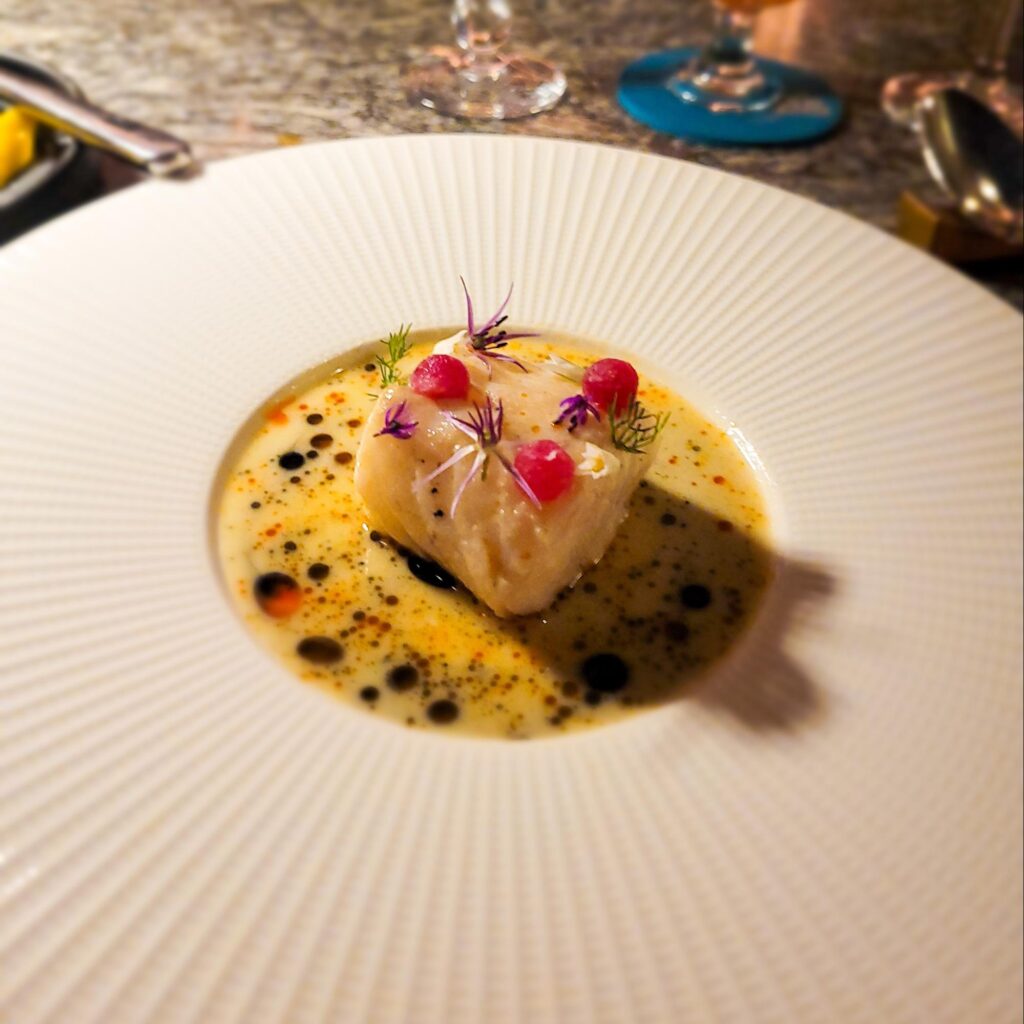 A delicately plated Icelandic Cod dish served at Lazy Betty, surrounded by a flavorful broth.