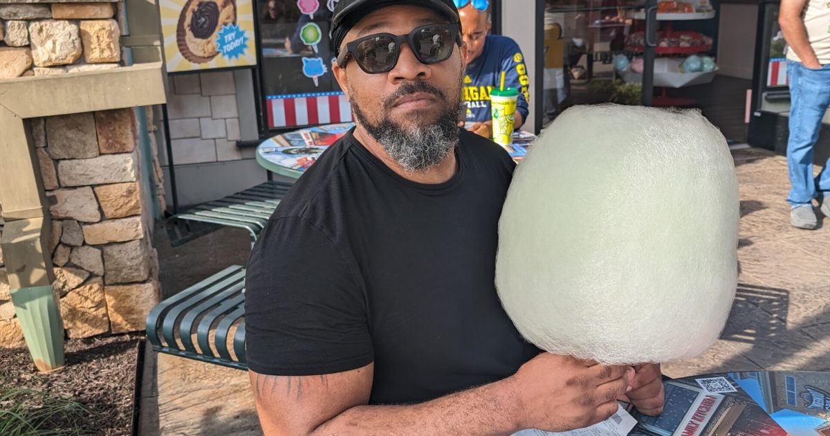 Man sitting at an outdoor table with a large cotton candy in Island Park in Pigeon Forge