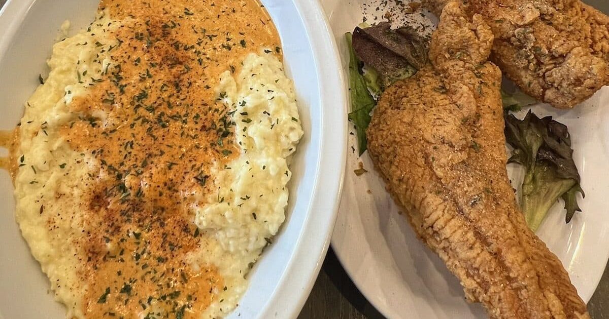 A plate of fish and grits served at Nouveau Bar & Grill in College Park, accompanied by hot sauce.