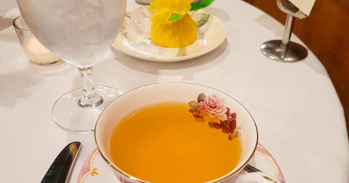 A floral tea cup filled with Passionfruit Dream Green Tea beside a glass of water at Afternoon Spring Tea, Ritz Carlton Atlanta.