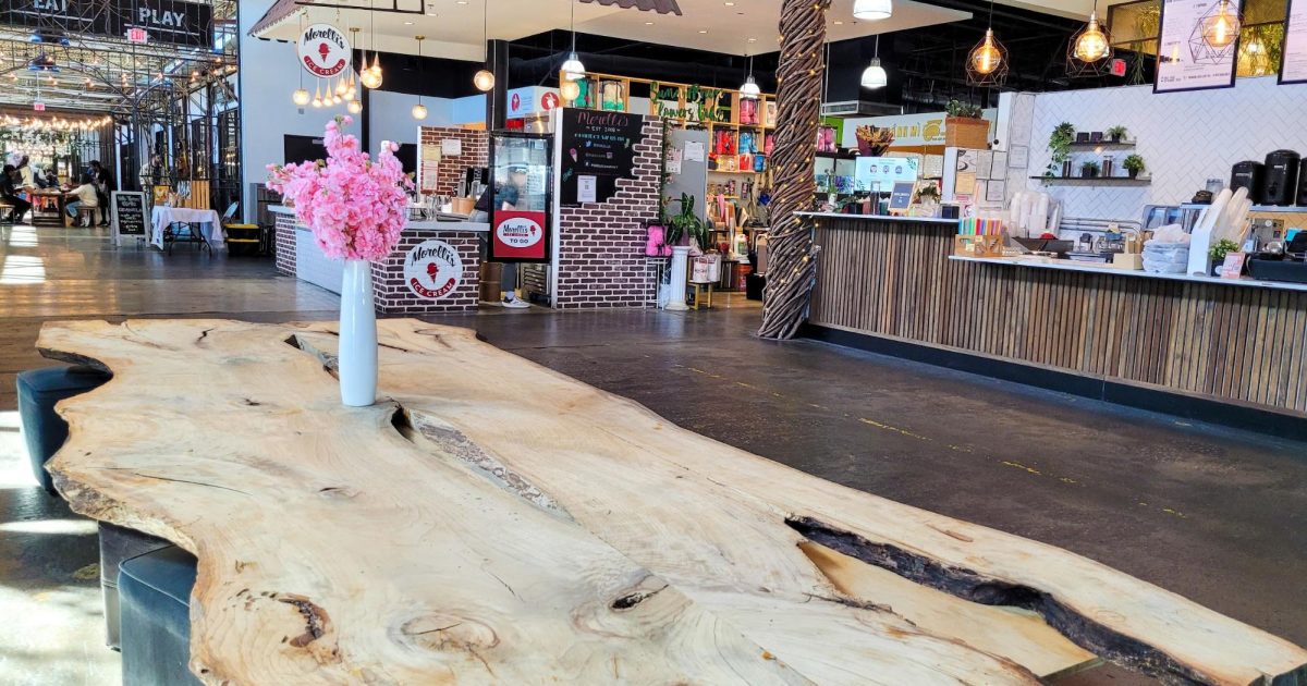 Interior of Chattahoochee Food Works with a large wooden table and food stalls.