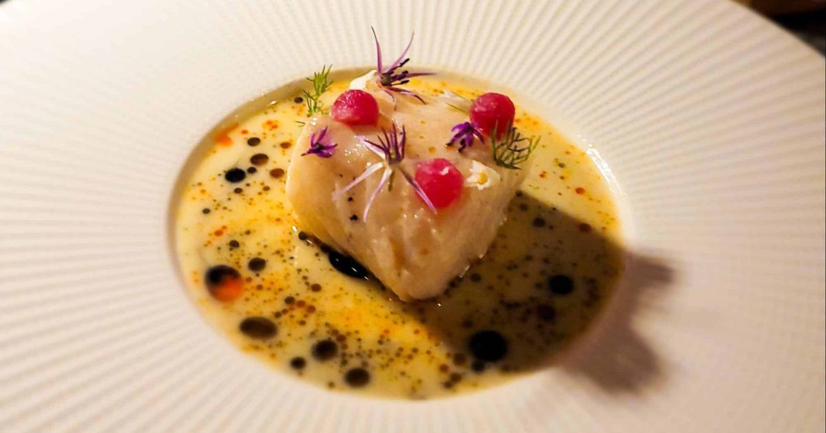 A delicately plated Icelandic Cod dish served at Lazy Betty, surrounded by a flavorful broth.