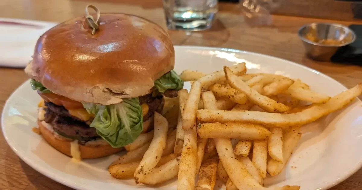 The B & G Burger, a juicy double stack smash burger with Swiss cheese, lettuce, tomato, and onion, served with fries.