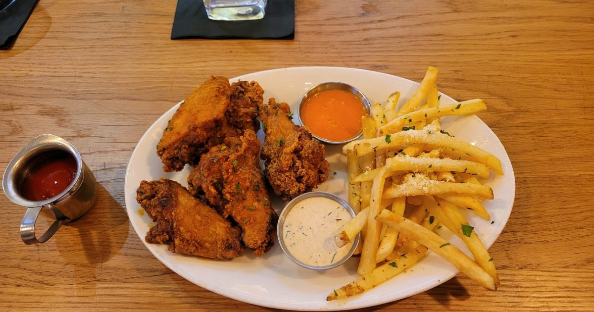 Crispy Everything Wings served with ranch sauce beside a portion of seasoned Truffle Fries at Marcus Bar & Grille.