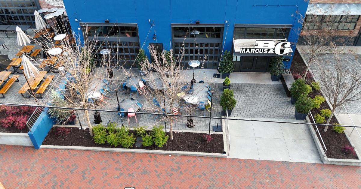 Aerial view of Marcus Bar & Grille's inviting outdoor seating area with wooden tables and string lights in Atlanta.