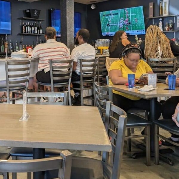 Interior view of Nouveau Bar & Grill in College Park, featuring diners at tables and the bar area with television screens.