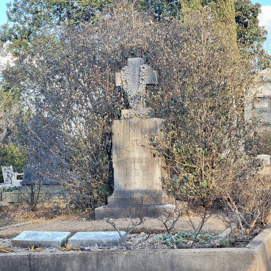 A weathered headstone surrounded by greenery at Oakland Cemetery.